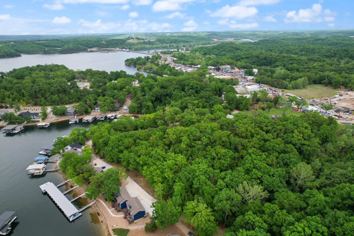 A picturesque scene featuring lakeside docks, vibrant green surroundings, and a quaint small town visible across the water. The docks hint at water activities, while the distant town suggests local exploration opportunities.
