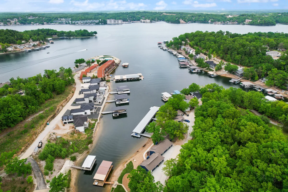 A broad view of the lake dotted with boats and surrounded by greenery and lakeside homes. The tranquil water invites boating, fishing, and relaxing, with hints of community and shared experiences nearby.