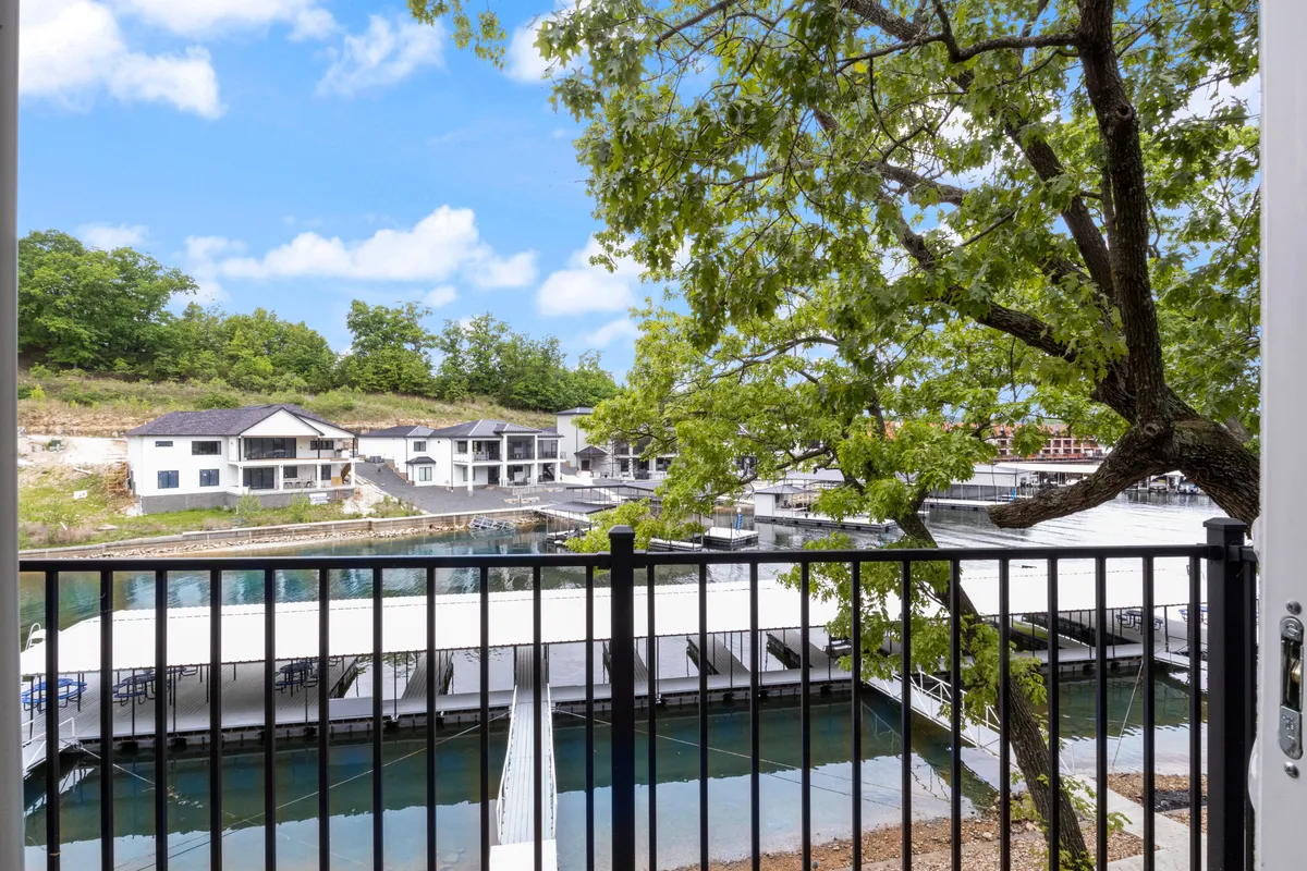The marina docks stretch out into tranquil blue water, framed by lush greenery and a clear sky. Boats dot the docks, suggesting boating adventures and water-based fun are just steps away. The serene, open atmosphere highlights the proximity to the lake and the variety of aquatic activities available.