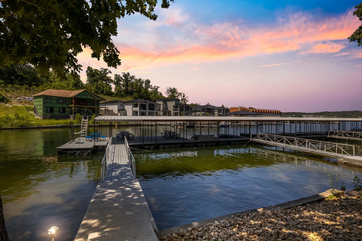 This image captures a serene lakeside dock at sunset, with calm waters reflecting the colorful sky. The dock is inviting, and there are buildings in the distance, underscoring a peaceful, family-friendly environment. The gentle water and tranquil setting are ideal for safe play and relaxation.